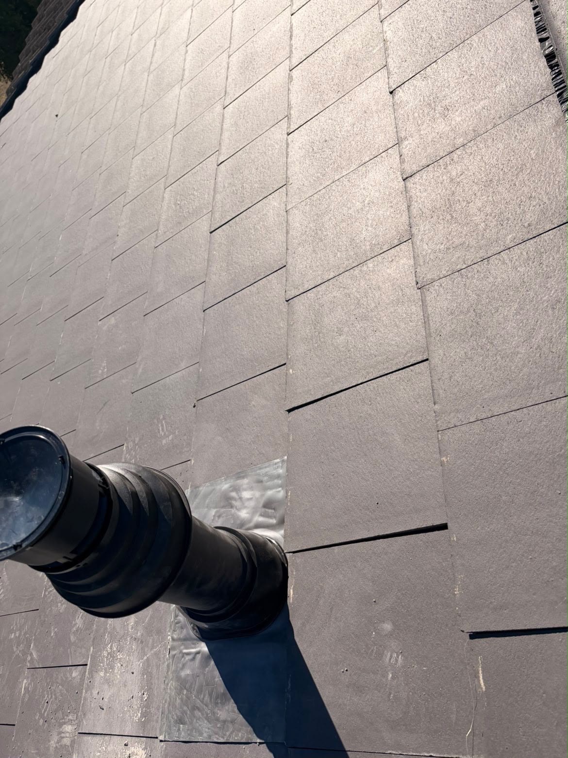 Lead flashing dressed around a soil vent pipe on a new slate roof